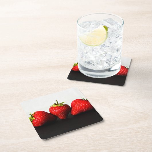 黒いコースタクナの上に白のイチゴ スクエアペーパーコースター (インサイチュ)