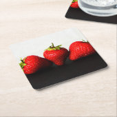 黒いコースタクナの上に白のイチゴ スクエアペーパーコースター (アングル)