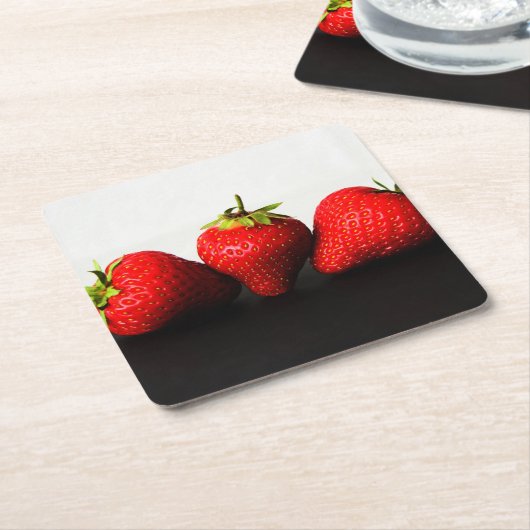 黒いコースタクナの上に白のイチゴ スクエアペーパーコースター (アングル)