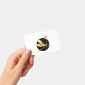 黒い円の中の金色のトンボ バッジ (手持ち)