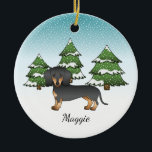 黒とタンの短い髪ダックスシュント – 冬の森 セラミックオーナメント<br><div class="desc">可愛い滑らかな髪の黒とタンコート色のデステイのオリジナル漫画のイラストレーションダッシュント品種の犬。3本の緑のモミの木と降り積もる雪が積もった冬のシーンに犬を置く。背景は青から白のグラデーション与えのデザインは、寒い冬の日に見える。名前にはパーソナル化可能な文字領域もある。</div>
