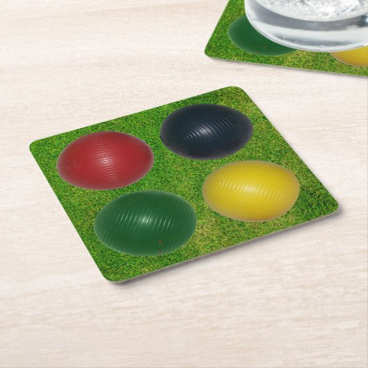 4つのクロケボール、4つの色、草の背景 スクエアペーパーコースター (アングル)