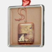 aの前にひざまずいている使用人を示しているInro メタルオーナメント (左)