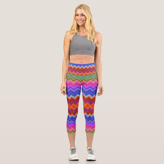 A woman wears vibrant, zigzag-patterned leggings  カプリレギンス (正面)