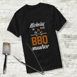 BBQマスターグリリングツールタイポグラフィカスタム Tシャツ<br><div class="desc">この楽しむBBQマスターデザインとカスタマイズテンプレート名。このオレンジと白のタイポグラフィは、炎と交差焼き具を持っている。</div>