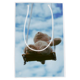 Beertje op schommel met bewolkte blauwe lucht. ミディアムペーパーバッグ