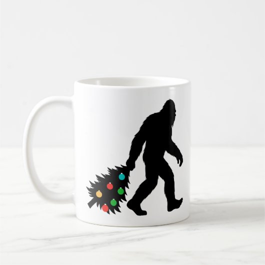 Bigfoot Dragging Christmas Tree  コーヒーマグカップ (左)