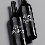 Black and White Brush Script Merry Christmas ワインラベル<br><div class="desc">Festive holiday wine labels featuring "Merry Christmas" displayed in white brush script lettering with a black background. Personalize the Merry Christmas wine labels with your family name and the year displayed in white lettering.</div>