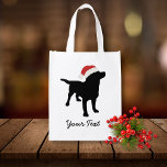 Black Lab Dog with Christmas Santa Hat エコバッグ<br><div class="desc">この可愛らしい黒いラボドッグデザインは、クリスマスサンタハットを着た黒いラブラドール赤と白レトリバーのシルエットを特徴とする。自分の文字でパーソナライズする – あなたの名前、クリスマスの挨拶、あなたの犬の名前など。クリスマスや冬の休日には、かわいいフェスティバルデザインを作る。背景の色を「on」クリックで変更しカスタマイズて、小さなスポイトをクリックする。ペット好き、子供、両親 – ちょうど誰もがZazzleのColorfugalshopのこの黒いお洒落ラボドッグのデザインを愛する。他のブラックラボデザインは下記のロゴクリックでを確認して下さい。感謝していストップ来て来い</div>