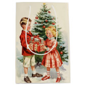 Boy and girl giving each other Christmas presents ミディアムペーパーバッグ (正面)
