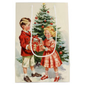 Boy and girl giving each other Christmas presents ミディアムペーパーバッグ (裏面)