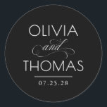 Chic Modern Minimalist Typography Black Wedding ラウンドシール<br><div class="desc">Minimalist black wedding seals place the couple’s names front and center — boldly presented and elegantly connected by a calligraphic “and” that adds a graceful,  romantic flourish.

Fully customizable to reflect your unique style — with adjustable text and background colors to perfectly complement your wedding aesthetic.</div>