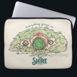 Everything Grows in THE SHIRE™ ラップトップスリーブ<br><div class="desc">Bring a little piece of Middle-Earth™ to your everyday with this charming Lord of the Rings™ design inspired by the cozy hills of Hobbiton. Featuring a storybook-style hobbit hole with its iconic round green door tucked into a lush hillside, the artwork is paired with the beloved phrase, “Everything grows in...</div>