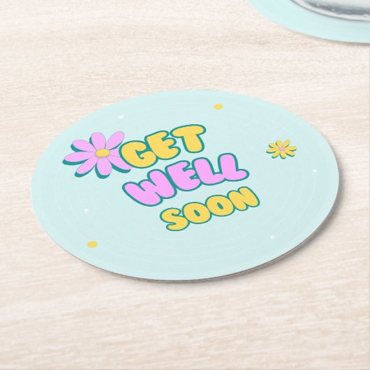 Get well soon bold text with flowers on blue ラウンドペーパーコースター (アングル)