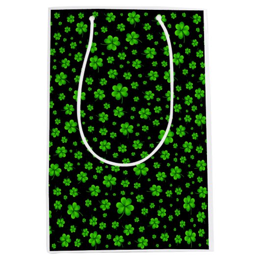 Pattern of green shamrocks on black background ミディアムペーパーバッグ (正面)