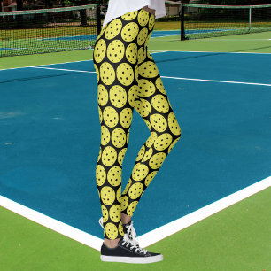 Pickleballのおもしろいな黄色い球および黒いスポーツ レギンス