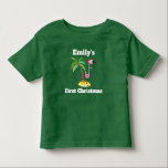 Red Santa Hat Christmas Personalでピンクのフラミンゴ トドラーTシャツ<br><div class="desc">名前と「初めてのクリスマス」パーソナライズされたを付けた幼児用Tシャツも変更できパーソナライズされたる。赤いサンタハットを着たピンクのフラミンゴのかわいいイラストレーションでデザイン。熱帯性のヤシの木を背にした砂の上に立つ。黒い色のTシャツに白いレタリング。</div>