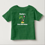 Red Santa Hat Christmas Personalでピンクのフラミンゴ トドラーTシャツ<br><div class="desc">名前と「初めてのクリスマス」パーソナライズされたを付けた幼児用Tシャツも変更できパーソナライズされたる。赤いサンタハットを着たピンクのフラミンゴのかわいいイラストレーションでデザイン。熱帯性のヤシの木を背にした砂の上に立つ。黒い色のTシャツに白いレタリング。</div>