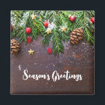 Rustic Christmas Table with Pine & Snow マグネット<br><div class="desc">Magnet with a rustic photograph of a brown wooden table with pinecones,  pine needles,  snow,  and Christmas ornaments. Festive and lovely.</div>