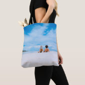 Two women lying on white sand facing beach under b トートバッグ (クローズアップ)