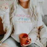TYRA 90をテーマにしたトロピック熱いバチェロレッテ Tシャツ<br><div class="desc">このバチェロレッテの花嫁シャツは、90年代をテーマにしたネオンフォントをセットに「暑いようね、結び目を結ぶ」という言葉を添えている。このシャツは「結び目を結んでいる」バチェロレッテと完璧に組み合わせている。</div>